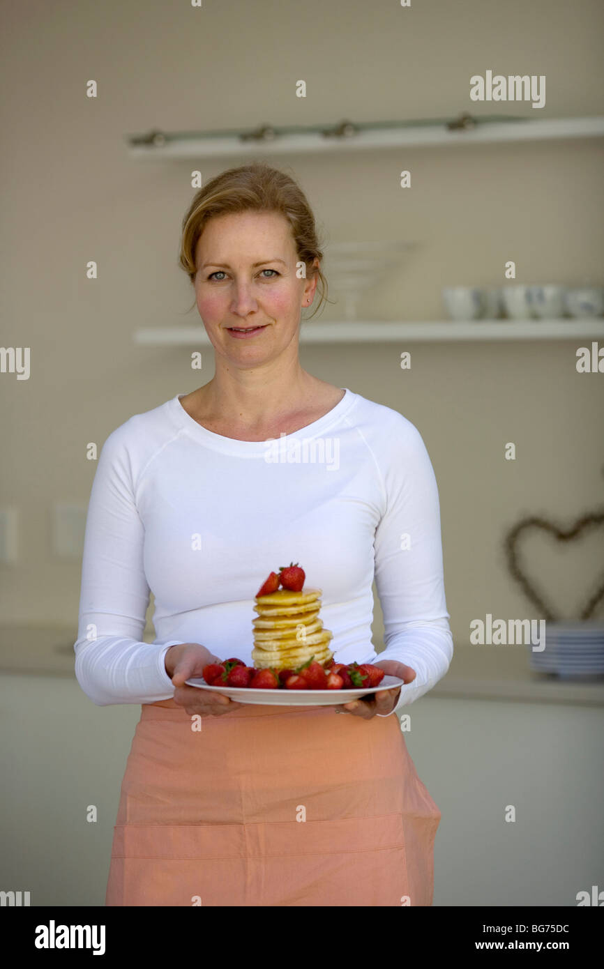 Mutter mit Haufen von Pfannkuchen mit Erdbeeren und Honig Sirup Stockfoto