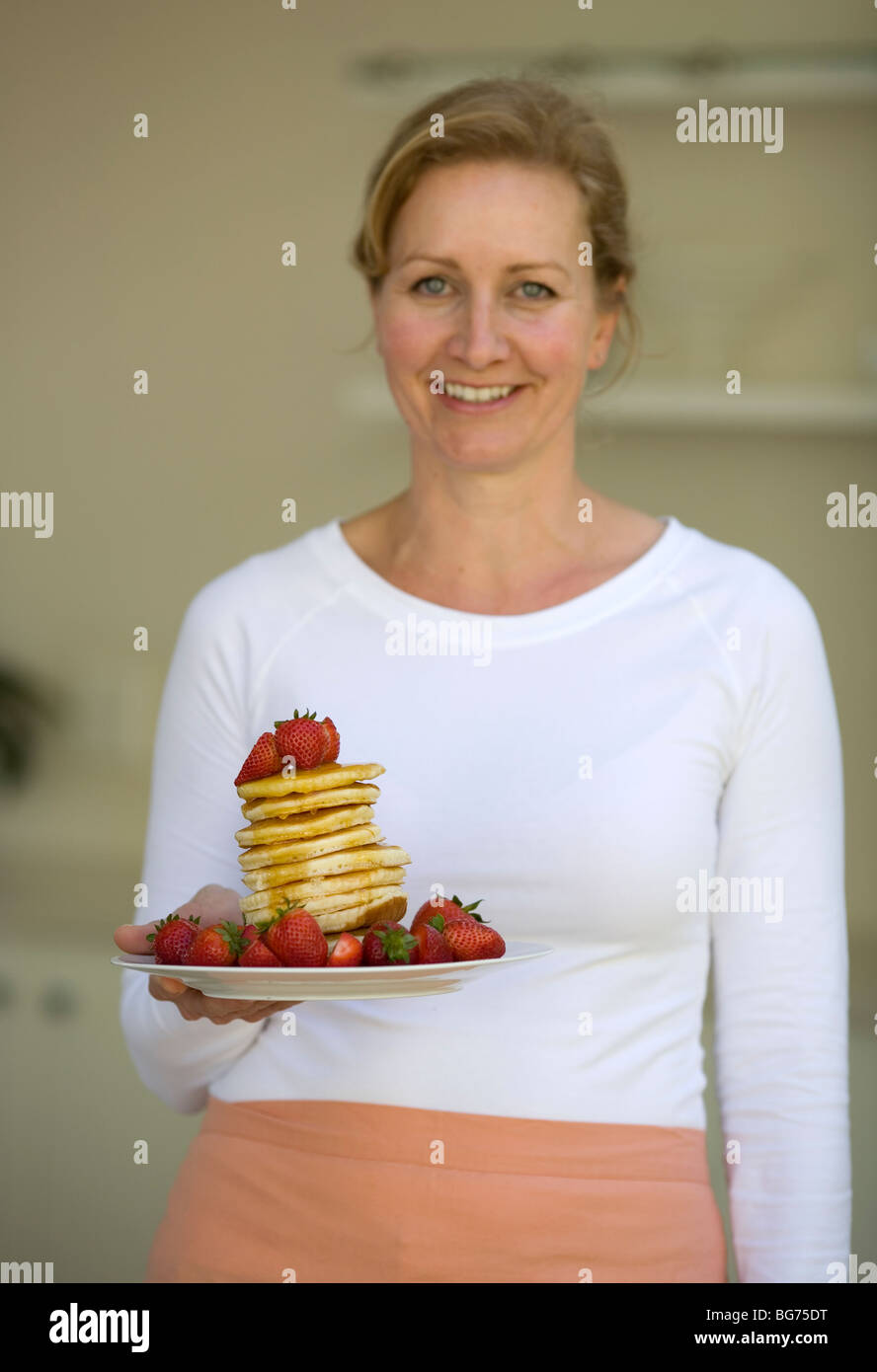 Mutter mit Haufen von Pfannkuchen mit Erdbeeren und Honig Sirup Stockfoto