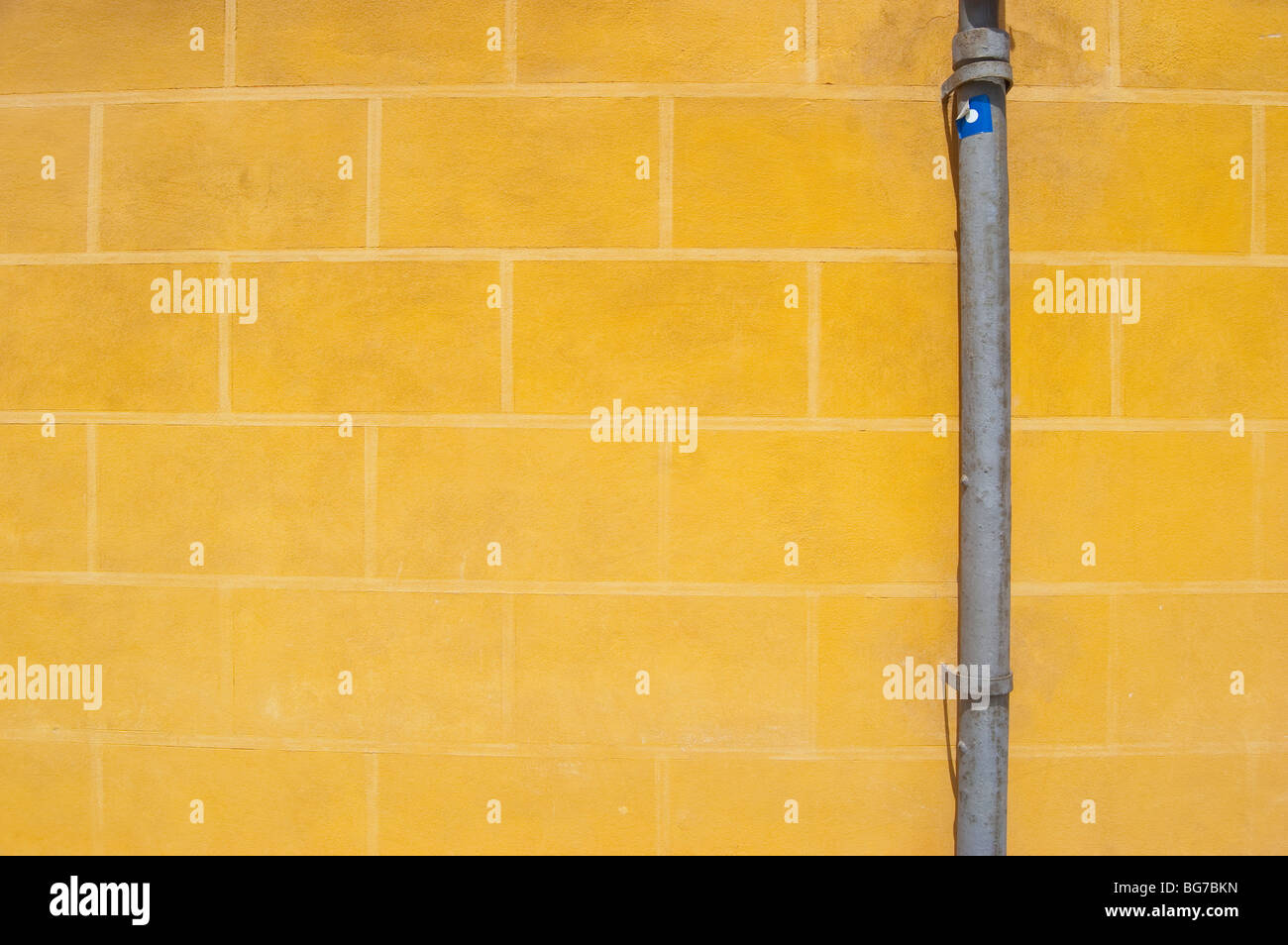 Graues Rohr auf schlichte gelbe Mauer. Stockfoto