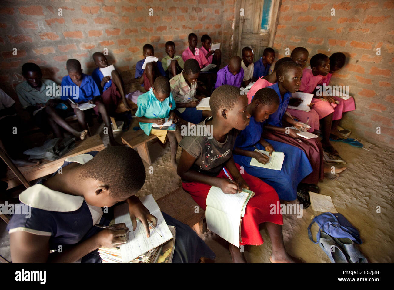Mädchen und Jungen lernen in einem dunklen Klassenzimmer ohne Schreibtische in Amuria, Osten Ugandas. Stockfoto
