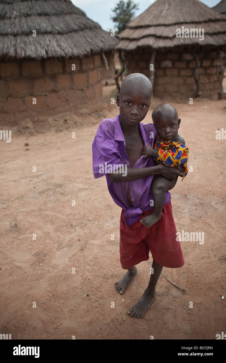 Ein Junge trägt ein kleines Kind in Acowa Flüchtlingslager in Amuria District, Uganda, Ostafrika. Stockfoto