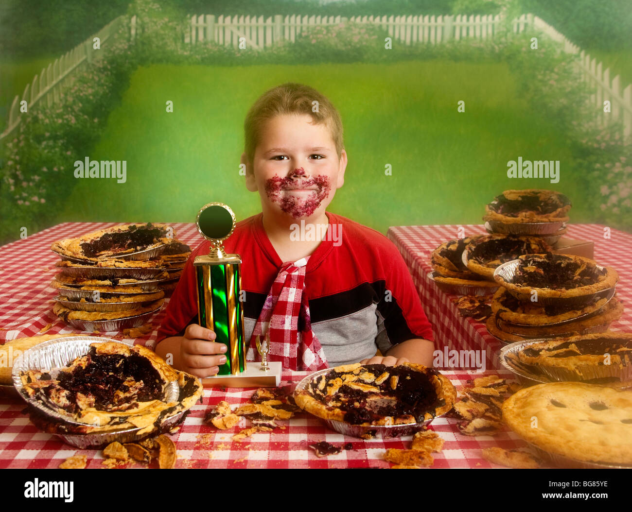 Mollige Junge am Ende einer Pie essen Wettbewerb mit der gewinnenden Medaille Stockfoto