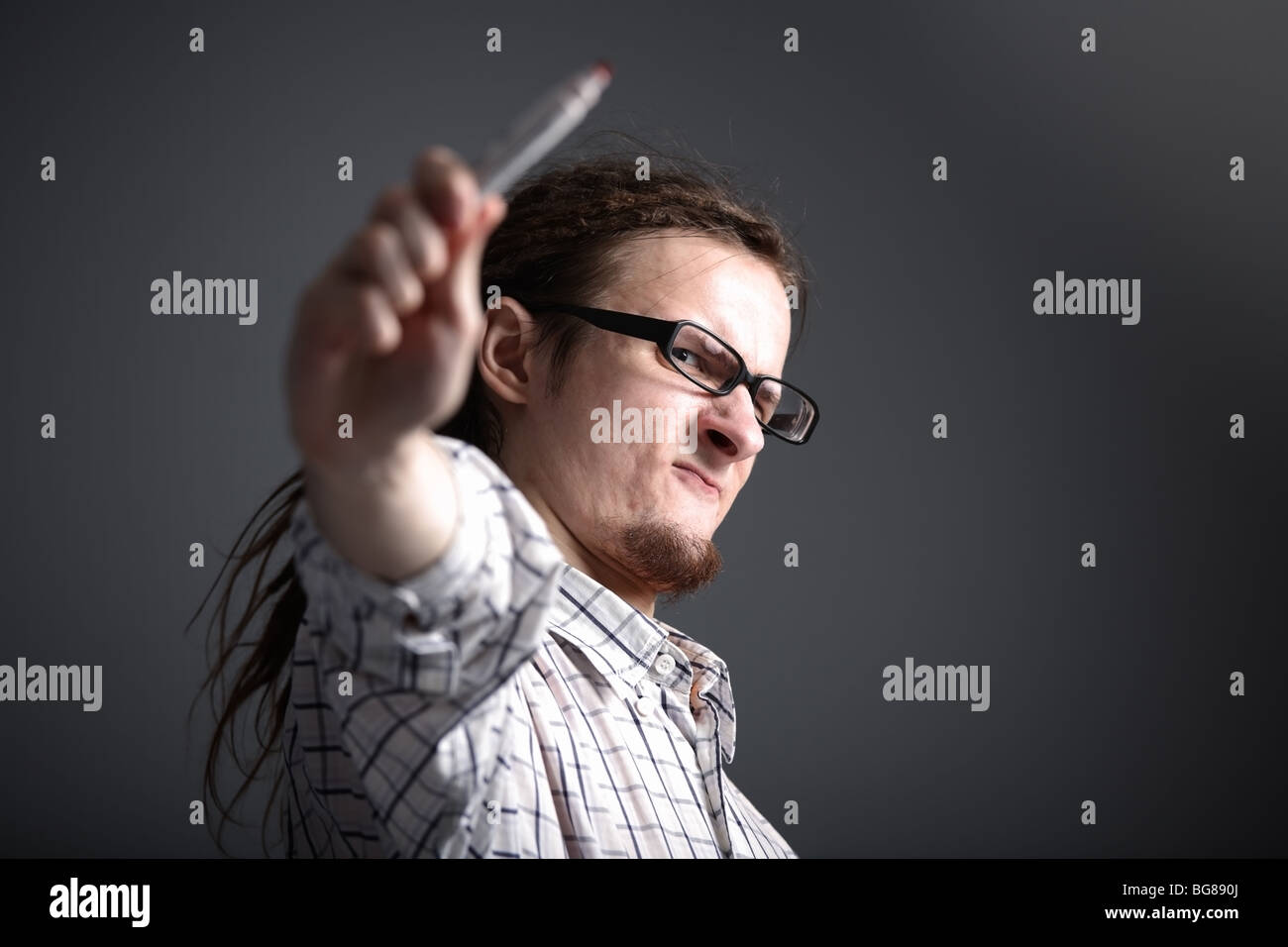 langhaarige exzentrischen Mann in Gläsern macht eine Geste der holding einer Markierung Stockfoto