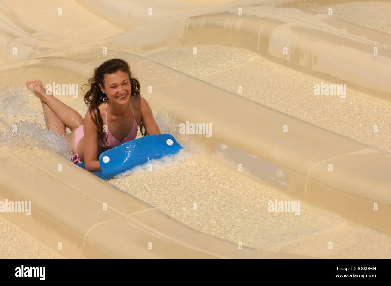 Junge lachende Frau auf einer Wasserrutsche in einen Wasserpark. Das Bild hat eine leichte Bewegungsunschärfe. Stockfoto
