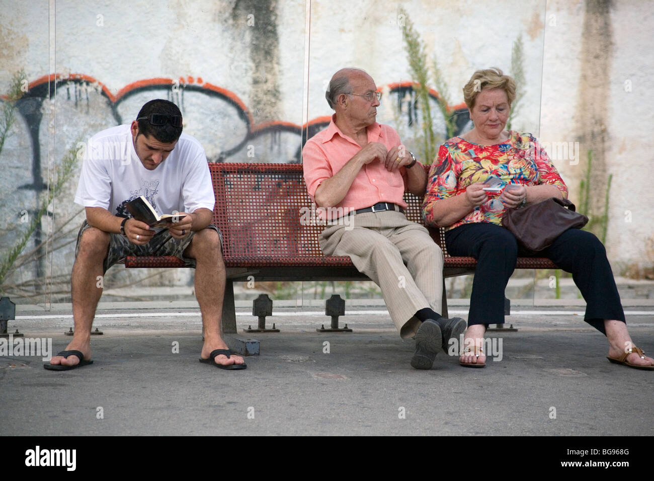 VOR MOBILTELEFONEN, 2007: Touristen warten und lesen auf dem Bahnsteig am Bahnhof Sitges in der Nähe von Barcelona Spanien in einer Zeit vor Mobiltelefonen Stockfoto