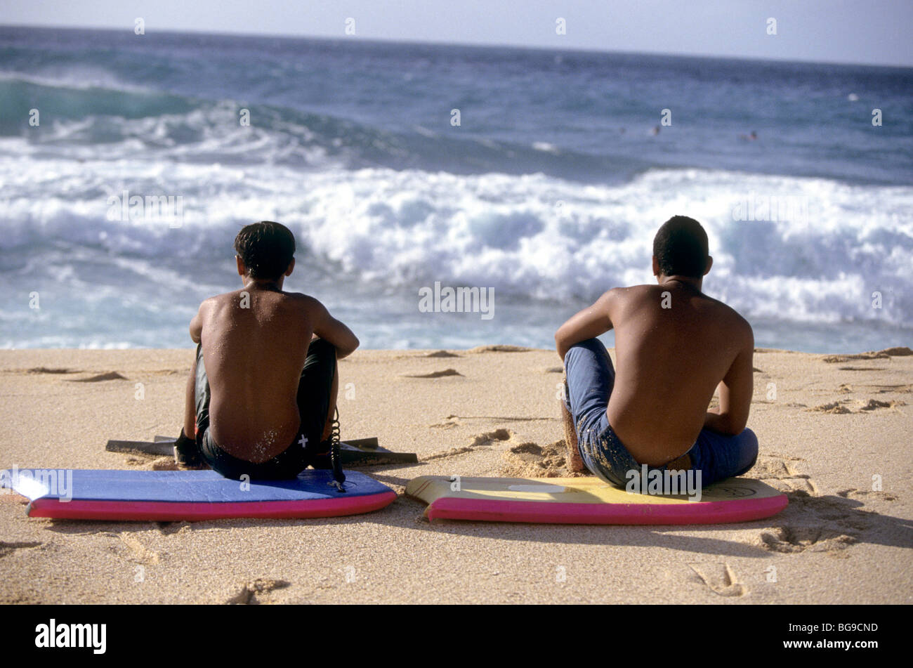 Zwei Jugendliche sitzen auf ihren Boogie-Boards, die Wellen zu beobachten Stockfoto