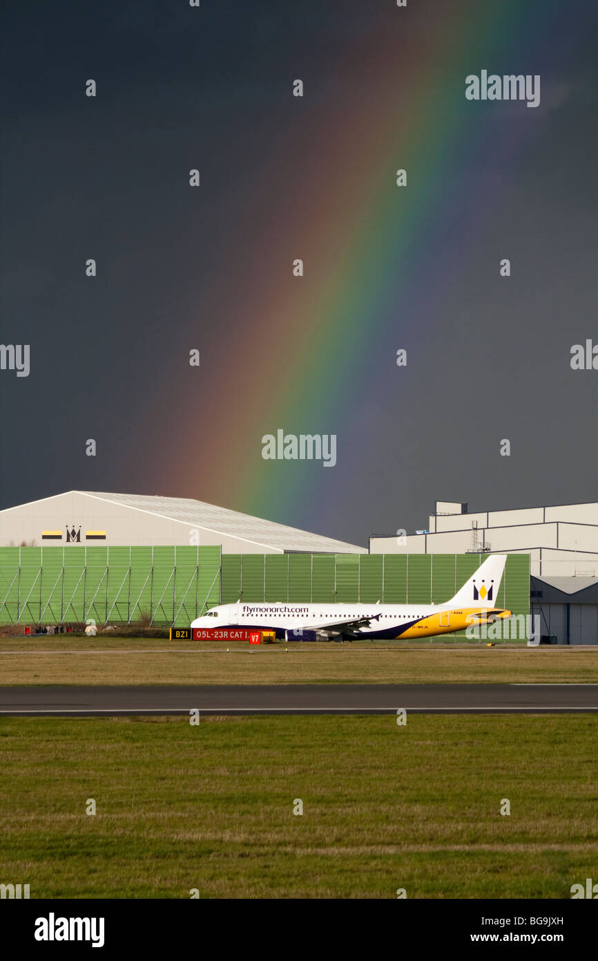 Monarch Airlines Airbus A320 Rollen vor ein Regenbogen am Manchester International Airport Stockfoto