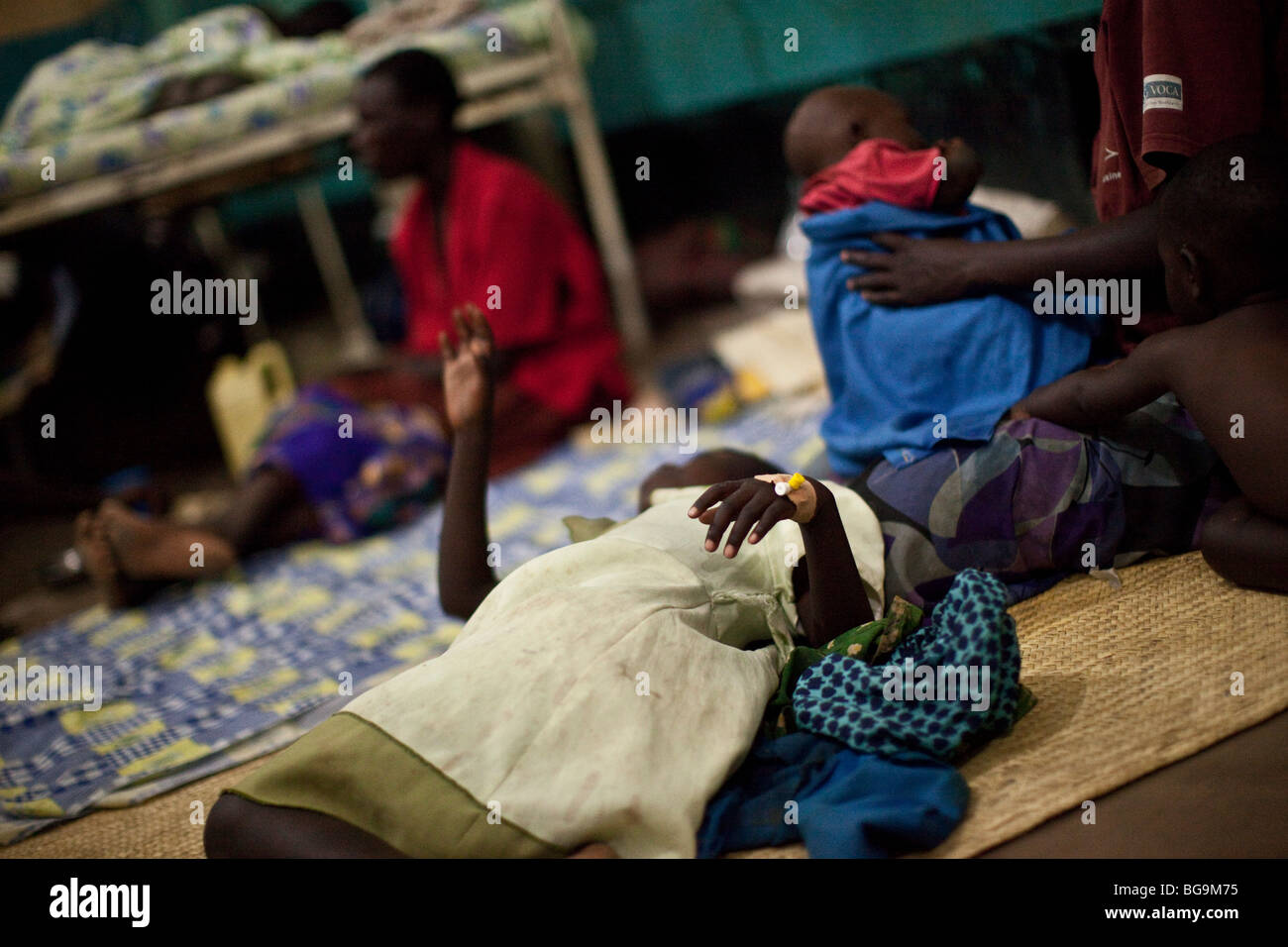 Ein Kind an Malaria liegt auf dem Boden eines überfüllten Krankenhauses in Amuria, Uganda, Ostafrika. Stockfoto
