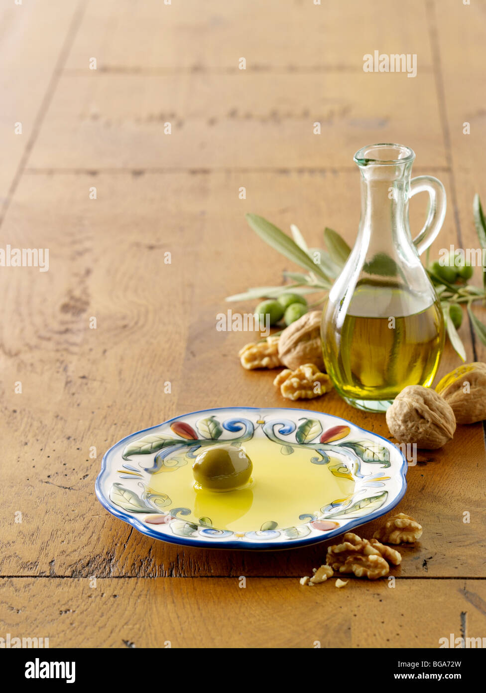 Olivenöl und Oliven auf Teller mit Walnüssen Stockfoto