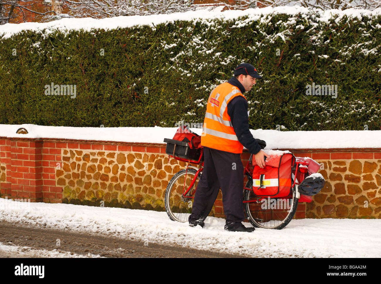 Ein Postbote kämpft sich durch den Schnee mit seinem Fahrrad die Weihnachtspost zu liefern. Stockfoto