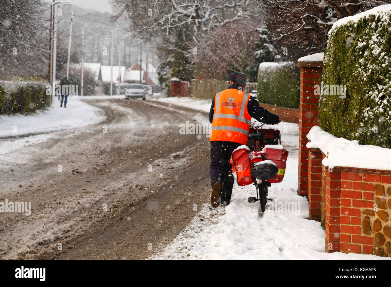 Ein Postbote kämpft sich durch den Schnee mit seinem Fahrrad die Weihnachtspost zu liefern. Stockfoto