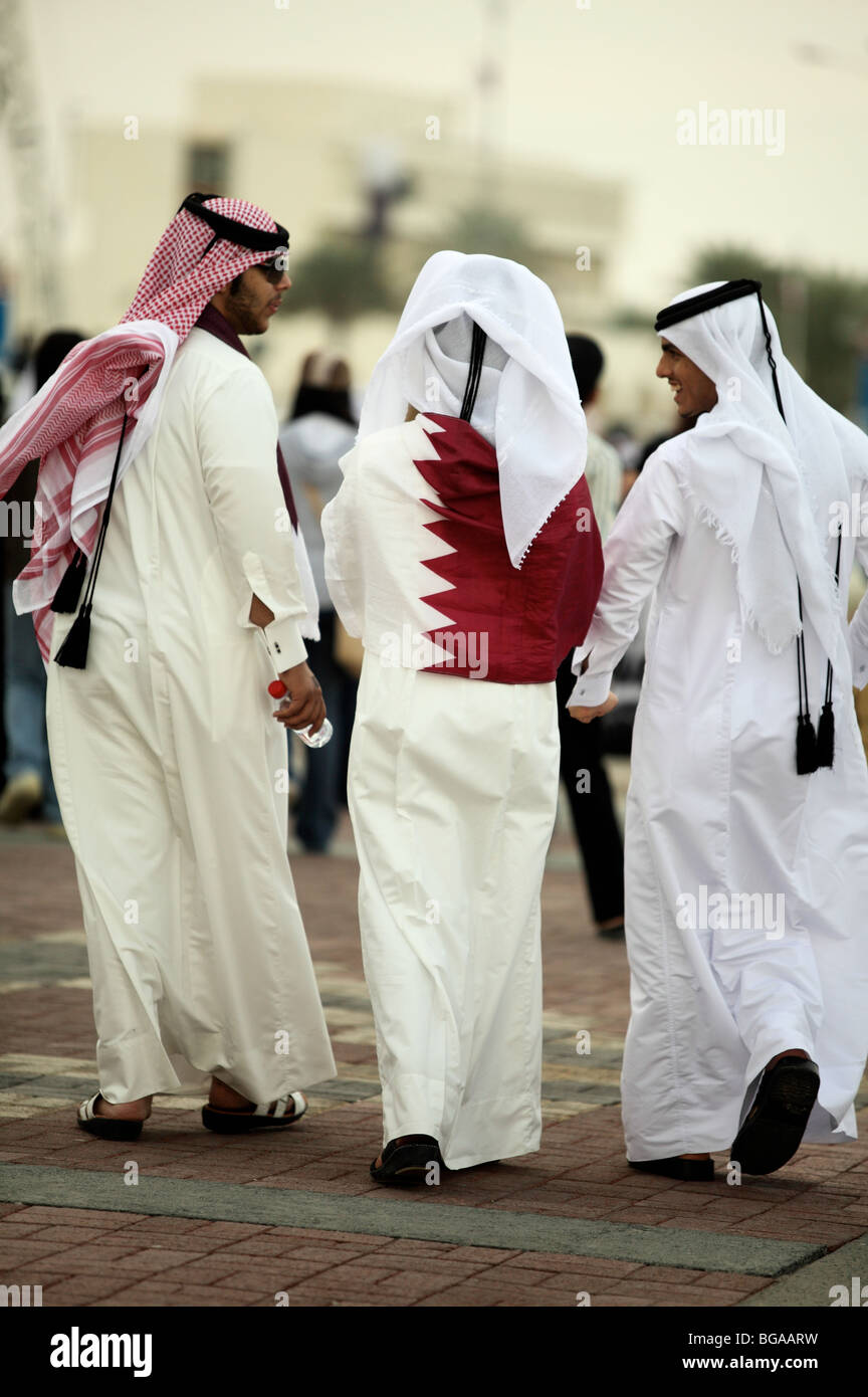 Begleitet von zwei Freunden katarischer Staatsangehöriger hüllt sich in Katars Flagge während der Feierlichkeiten zum Nationalfeiertag am Doha Corniche, Stockfoto
