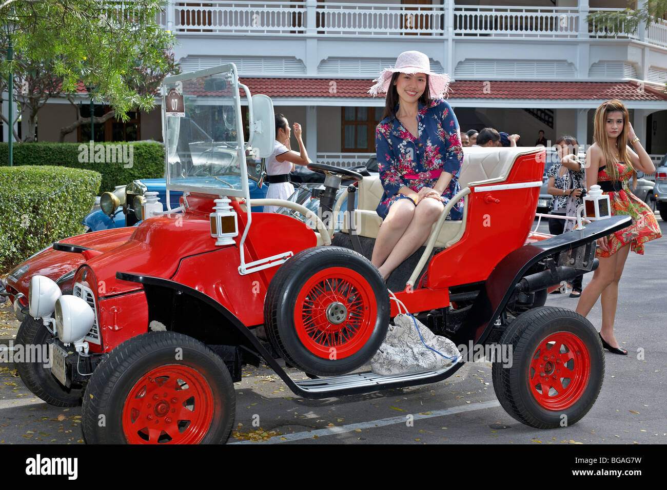 Weibliches Modell, das sich mit einem roten, auf Volkswagen basierenden Cabriolet posiert. Durchgehende Seitenansicht. Thailand Südostasien Stockfoto