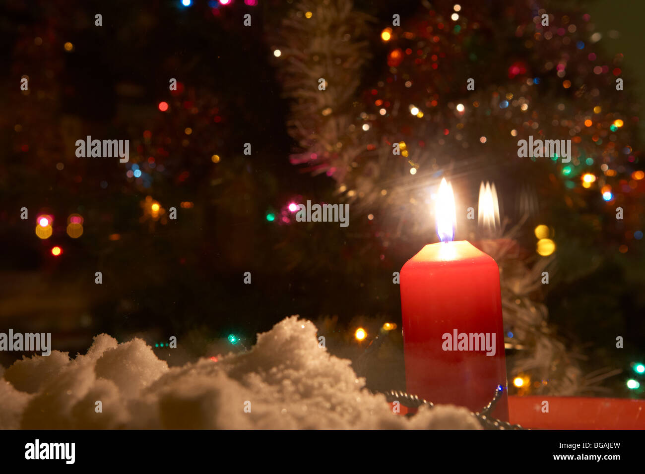 Kerze in das Fenster eines Hauses mit Weihnachtsbaum im Vereinigten Königreich mit Schnee auf der Fensterbank Stockfoto