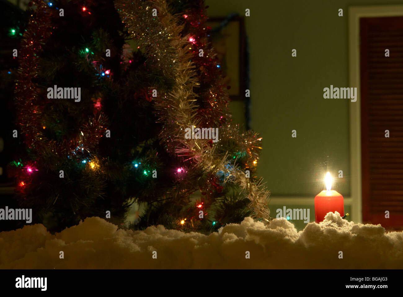 Kerze in das Fenster eines Hauses mit Weihnachtsbaum im Vereinigten Königreich mit Schnee auf der Fensterbank Stockfoto