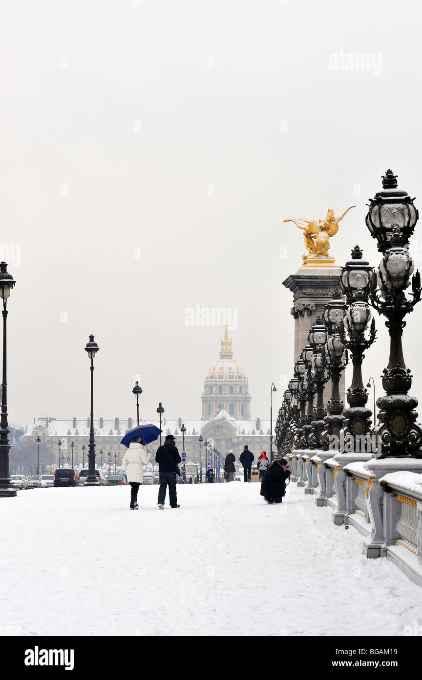 Paris, Frankreich, Winter kleine Gruppe von Menschen im Schneesturm, Paar Touristen, die auf der Brücke „Pont Alexandre III“ laufen, mit dem Invalidengebäude hinten Stockfoto