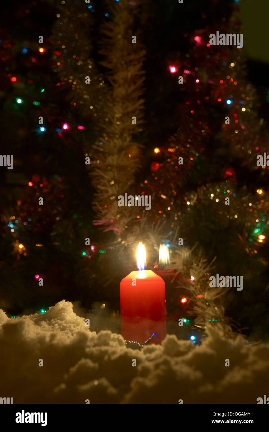 Kerze in das Fenster eines Hauses mit Weihnachtsbaum im Vereinigten Königreich mit Schnee auf der Fensterbank Stockfoto