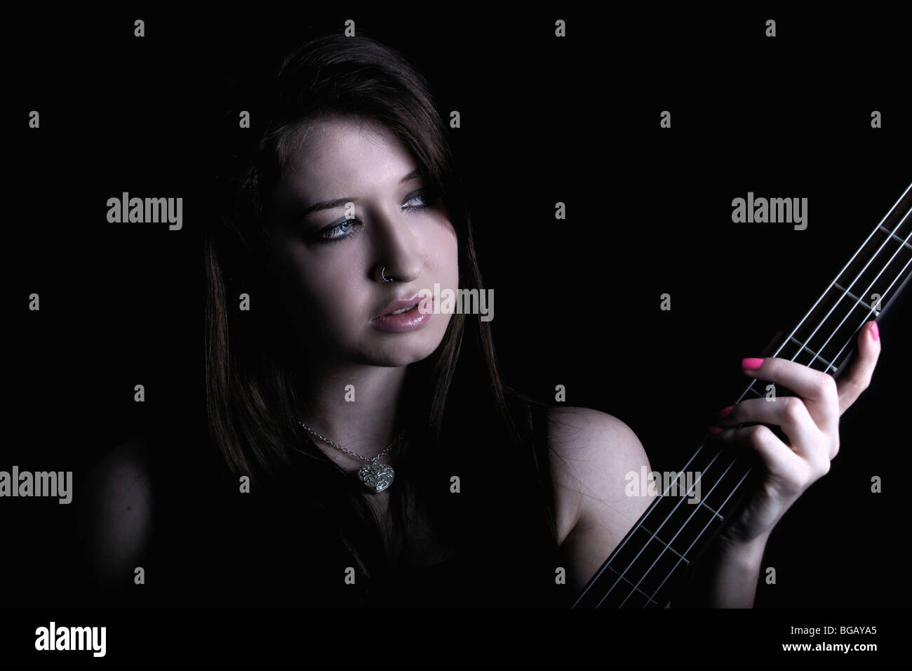 eine trendige junge Frau spielt die Bass-Gitarre Stockfoto