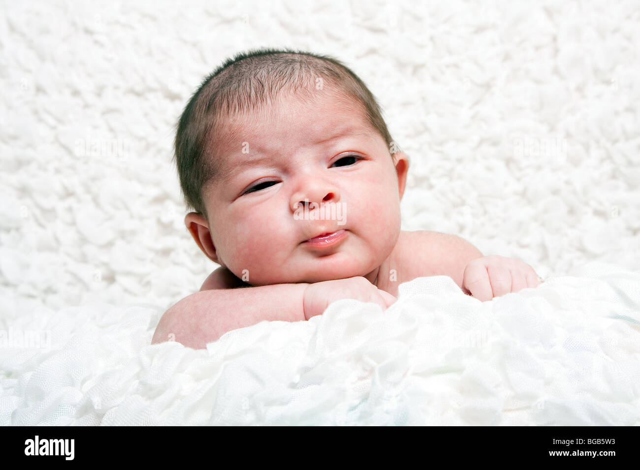 Süßes kaukasischen Hispanic Säugling Baby Gesicht mit lustigen Ausdruck auf weiche weiße Baumwolle Wolke. Stockfoto