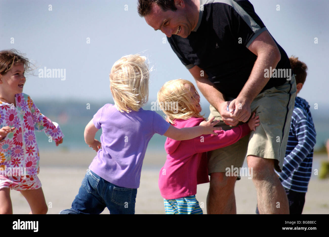 Lizenzfreie kostenlose Foto von Vater mit seinen Kindern am Strand spielen, im Sommerurlaub UK Stockfoto