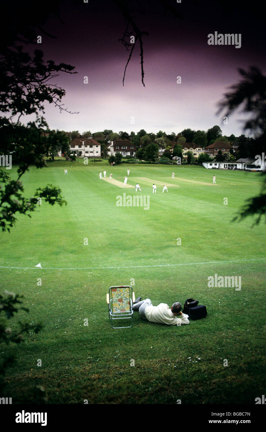 Zuschauer sitzen unter einem Baum ein Cricket-Match beobachten Stockfoto