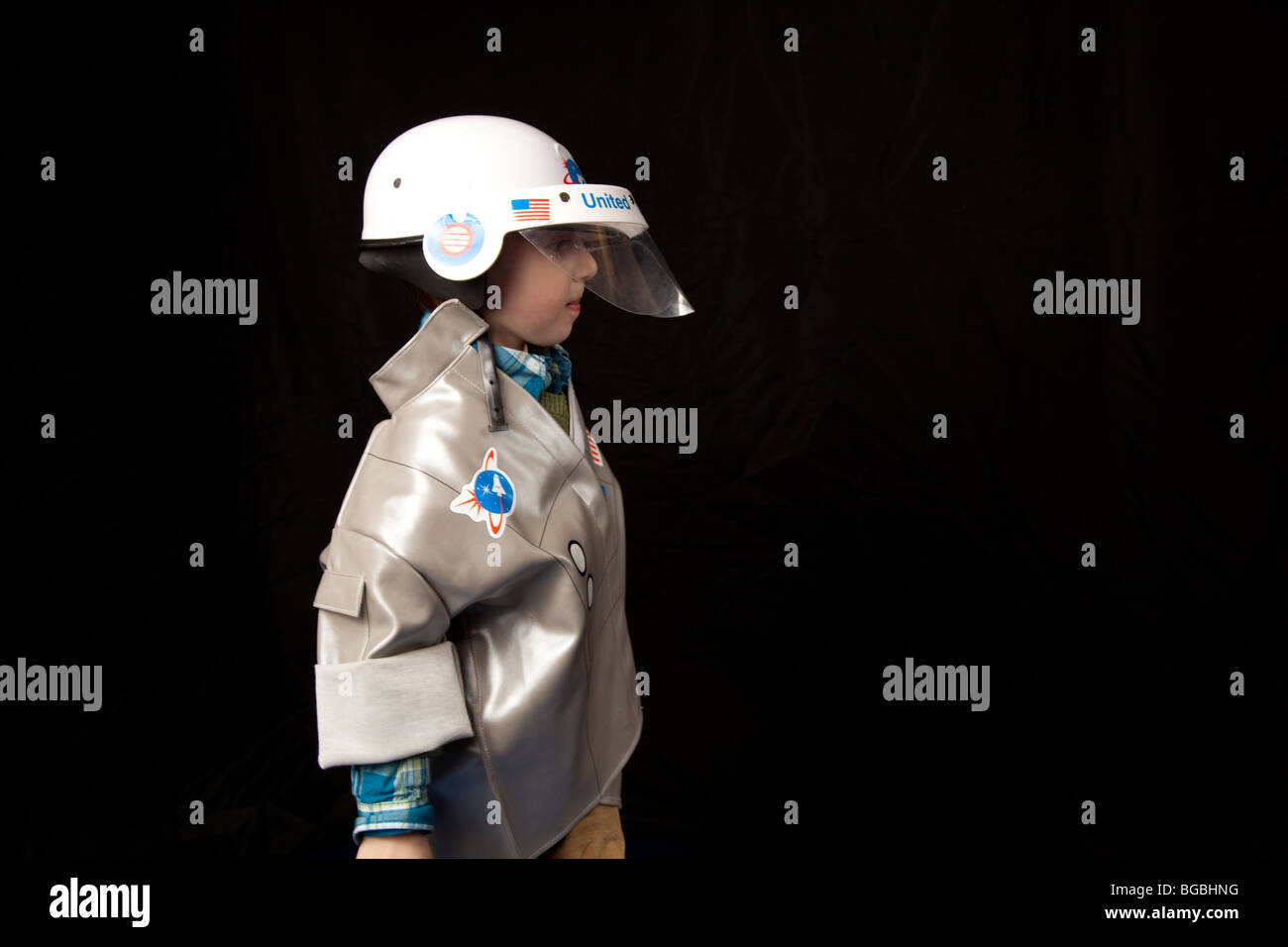 ein Junge im Profil in einem Raumanzug Kostüm mit Helm auf schwarzem Hintergrund Stockfoto