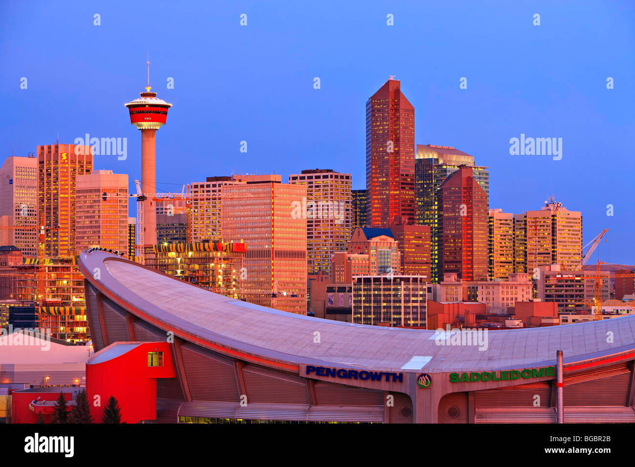 Der Saddledome mit Hochhäusern und dem Calgary Tower im Hintergrund bei Sonnenaufgang, Stadt von Calgary, Alberta, Kanada. Stockfoto