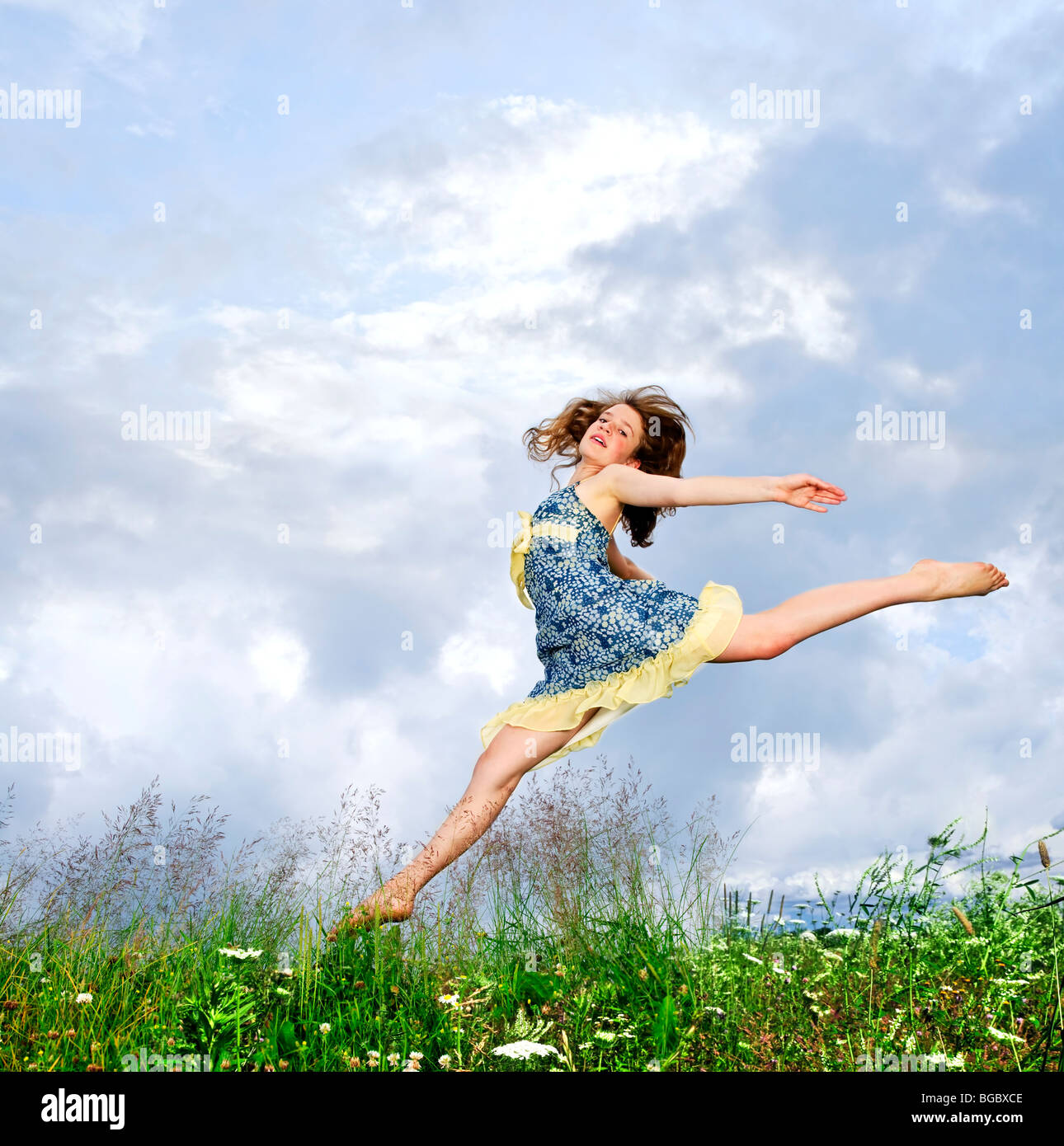 Junge Teenager-Mädchen springen in Sommerwiese inmitten von Wildblumen Stockfoto