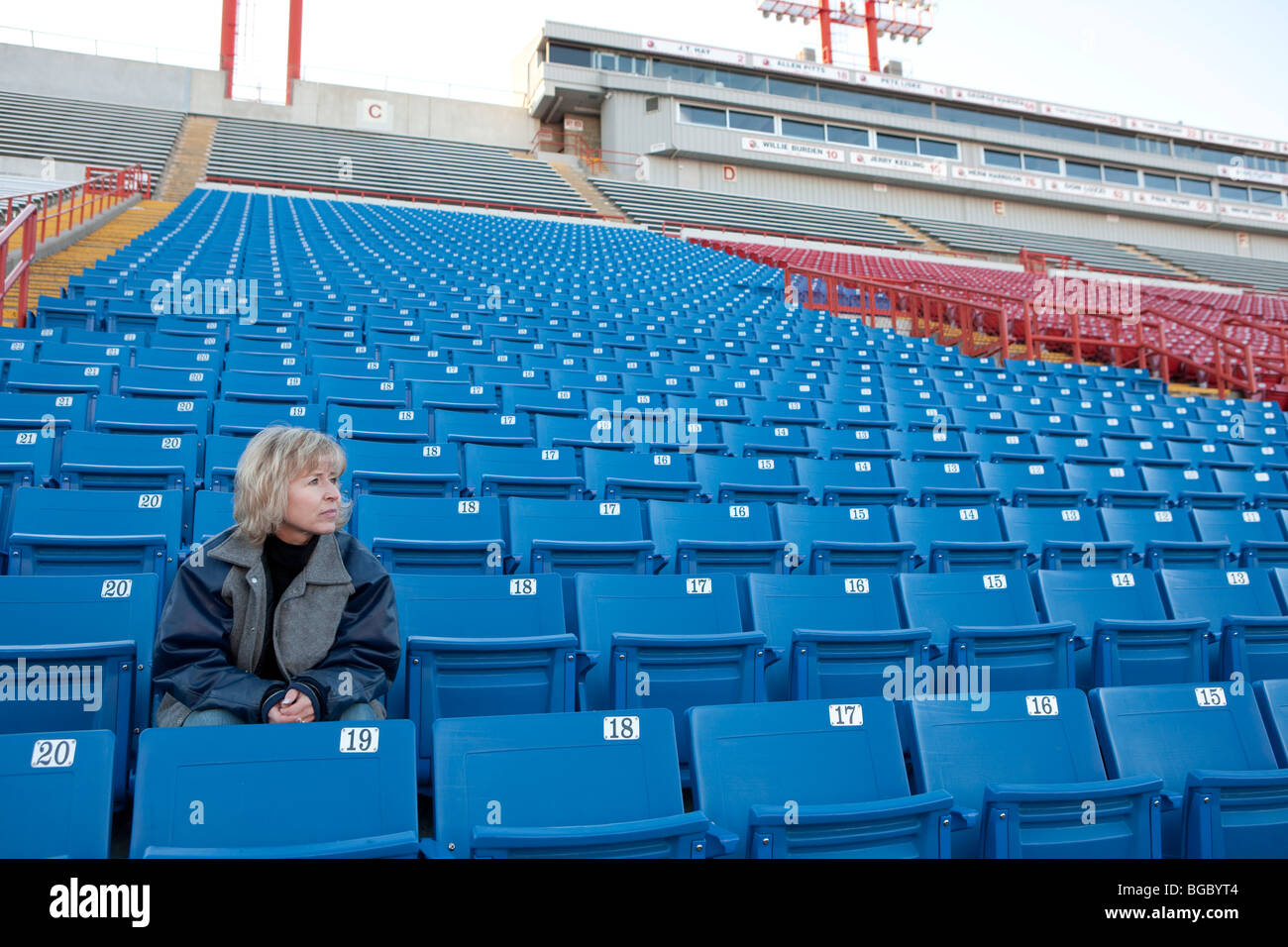 Frau sitzt alleine in Stadionsitze Stockfoto