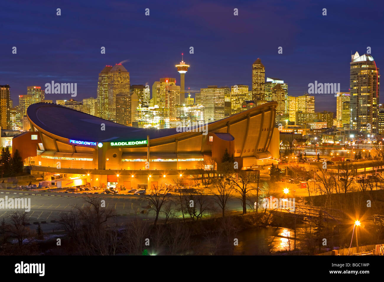 Der Saddledome mit Hochhäusern und dem Calgary Tower im Hintergrund in der Abenddämmerung, Stadt von Calgary, Alberta, Kanada. Stockfoto