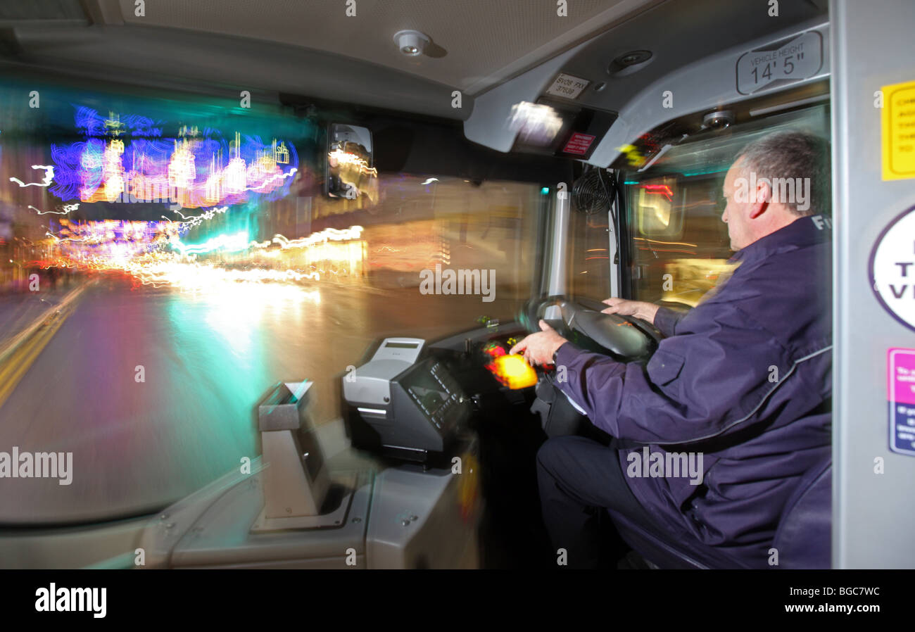 Busfahrer in Großbritannien fahren seine öffentlichen Fahrzeugbus nachts in einer Stadt Stockfoto
