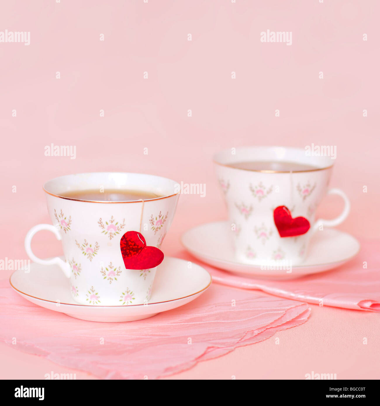 zwei Tassen mit Herzen auf rosa Hintergrund Stockfoto