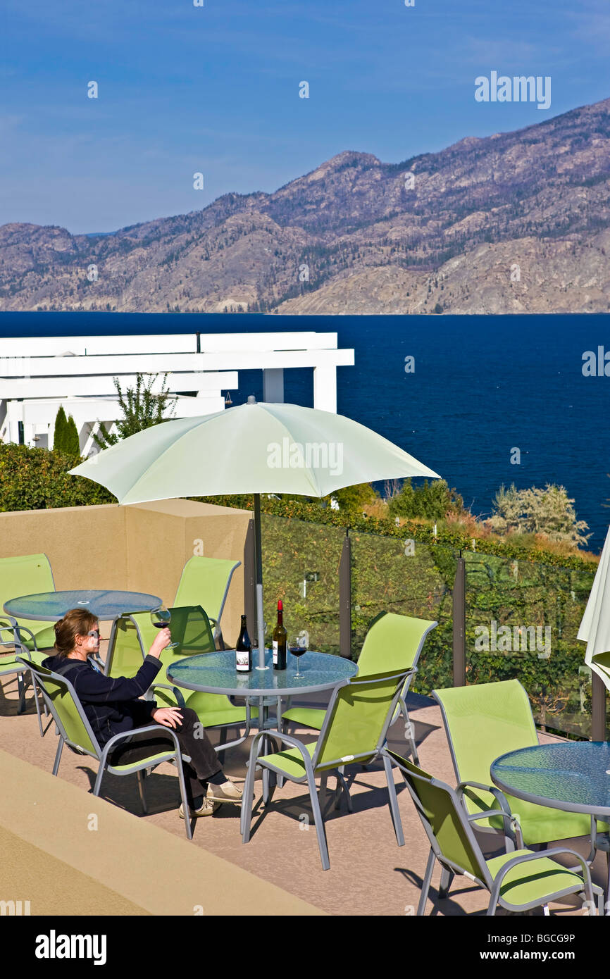 Frau sitzt an einem Tisch auf der Terrasse mit einer Flasche Wein im Weingut Bonitas, Summerland, Okanagan-Similkameen Region, Okanag Stockfoto