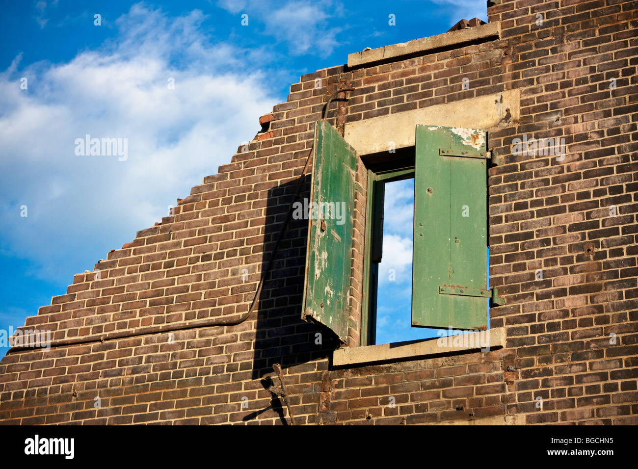 Konzeptionelle Schuss eines abgerissenen Gebäudes. Einwandige bleibt mit einem Fenster, blauem Himmel und weißen Wolken. Stockfoto