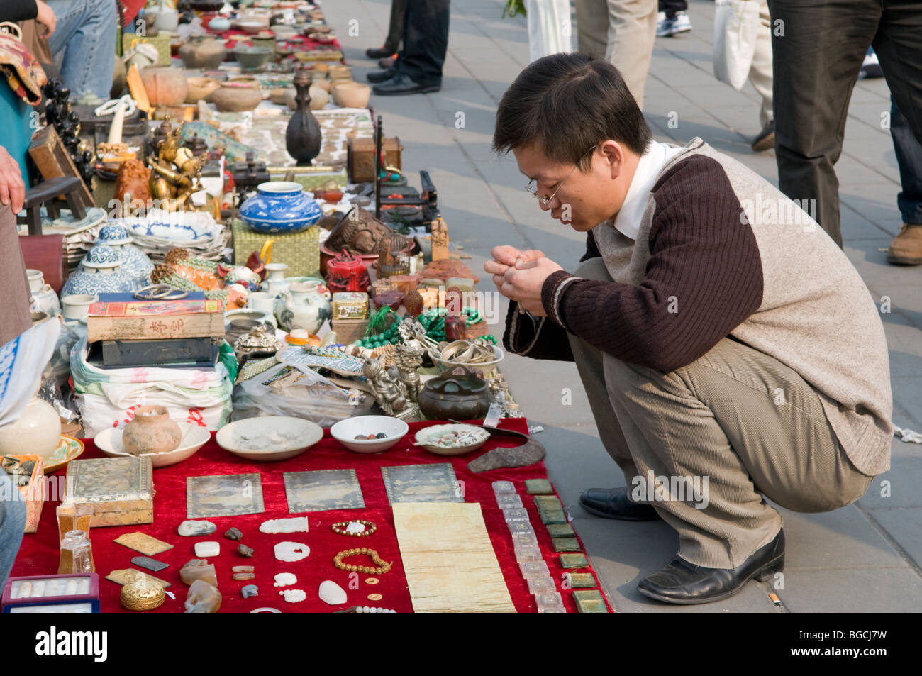 Ein Mann inspiziert waren an den Schmutz-Markt, auch genannt der Antikmarkt Panjiayuan in Peking China Stockfoto