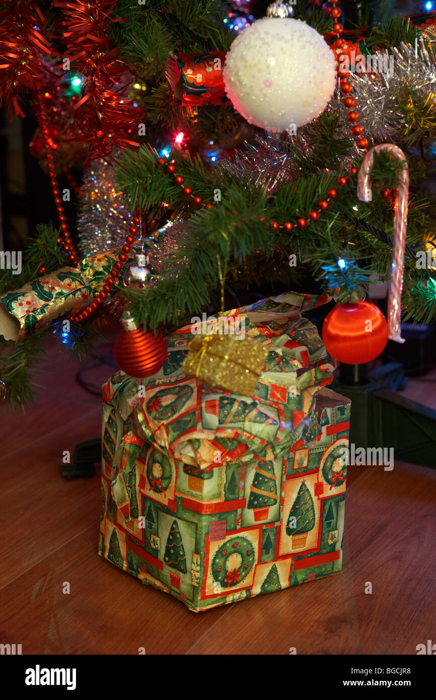 schlecht verpackte einziges Weihnachtsgeschenk unter Weihnachtsbaum zu Weihnachten in Großbritannien Stockfoto