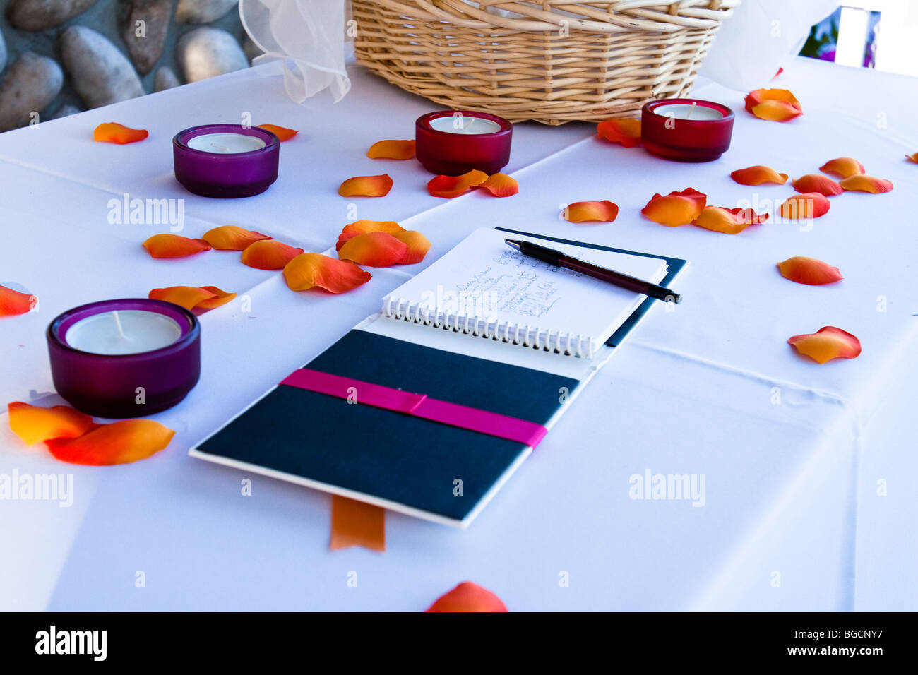 Hochzeit Gästebuch mit Unterschriften auf einem Tisch mit Blütenblättern und Votiv-Kerzen Stockfoto