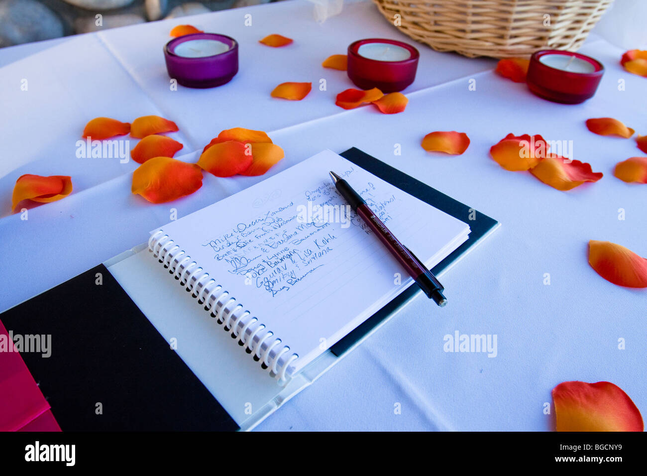Hochzeit Gästebuch mit Unterschriften auf einem Tisch mit Blütenblättern und Votiv-Kerzen Stockfoto