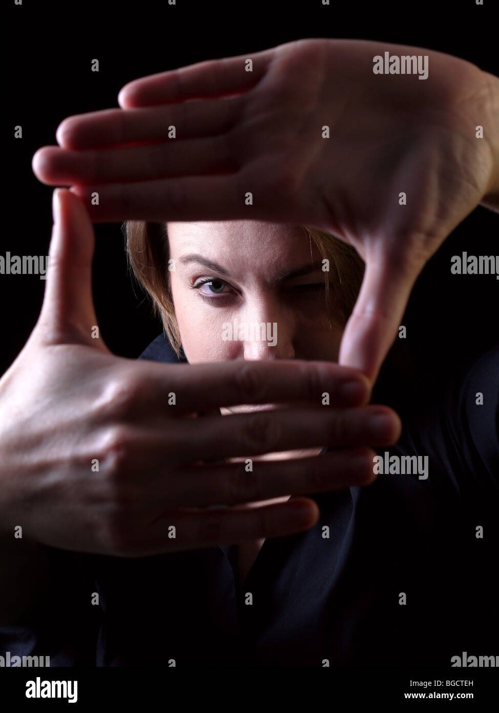 Frau, die ihr Gesicht mit den Händen - low-Key-Effekt Rahmung Stockfoto
