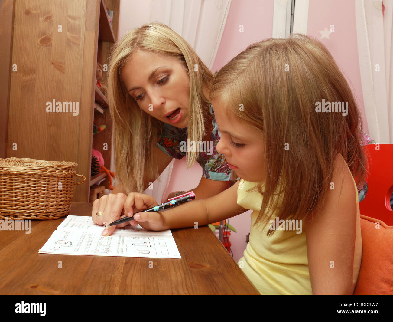 Mutter, Lehre ihrer kleinen Tochter schreiben im Heft Stockfoto