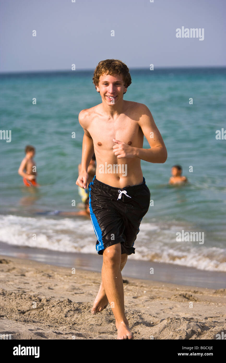 Teen Junge läuft in Badehose und am Strand, Lächeln, Porträt, Lächeln, Porträt Stockfoto