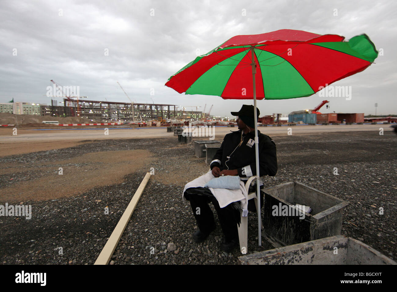 Ein Mann sitzt unter einem Sonnenschirm bei schlechtem Wetter, Dubai, Vereinigte Arabische Emirate Stockfoto