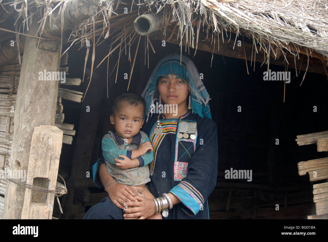 Armut, Akha Nuqui Frau mit einem Kleinkind auf dem Schoß in indigo farbigen Trachten gekleidet, mit einem Tuch Kopfbedeckung Stockfoto