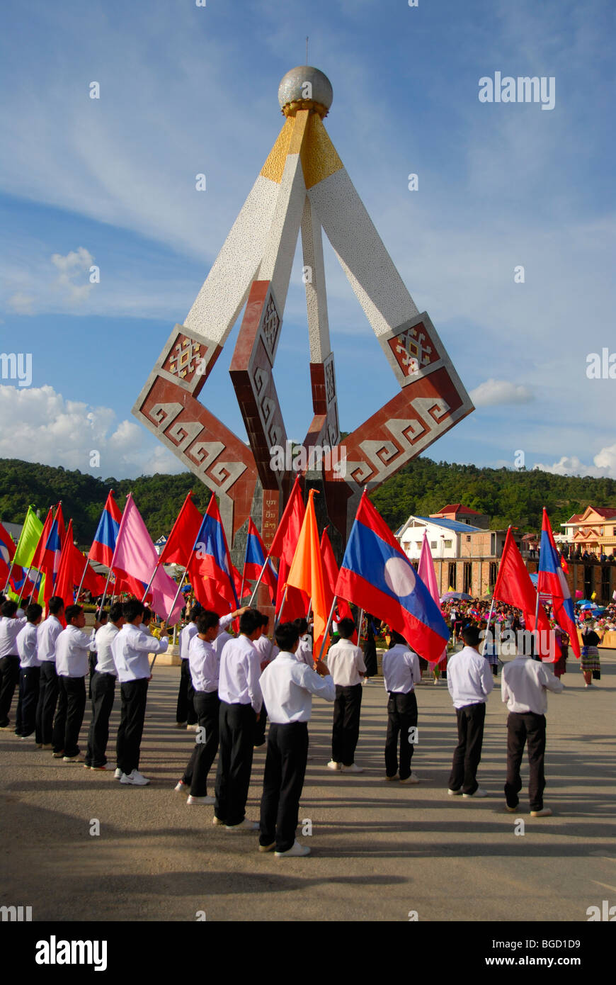 Festival, junge Männer von der Lao-Jugendorganisation mit bunten Fahnen vor einem Denkmal, Xam Neua, Provinz Houaphan Stockfoto