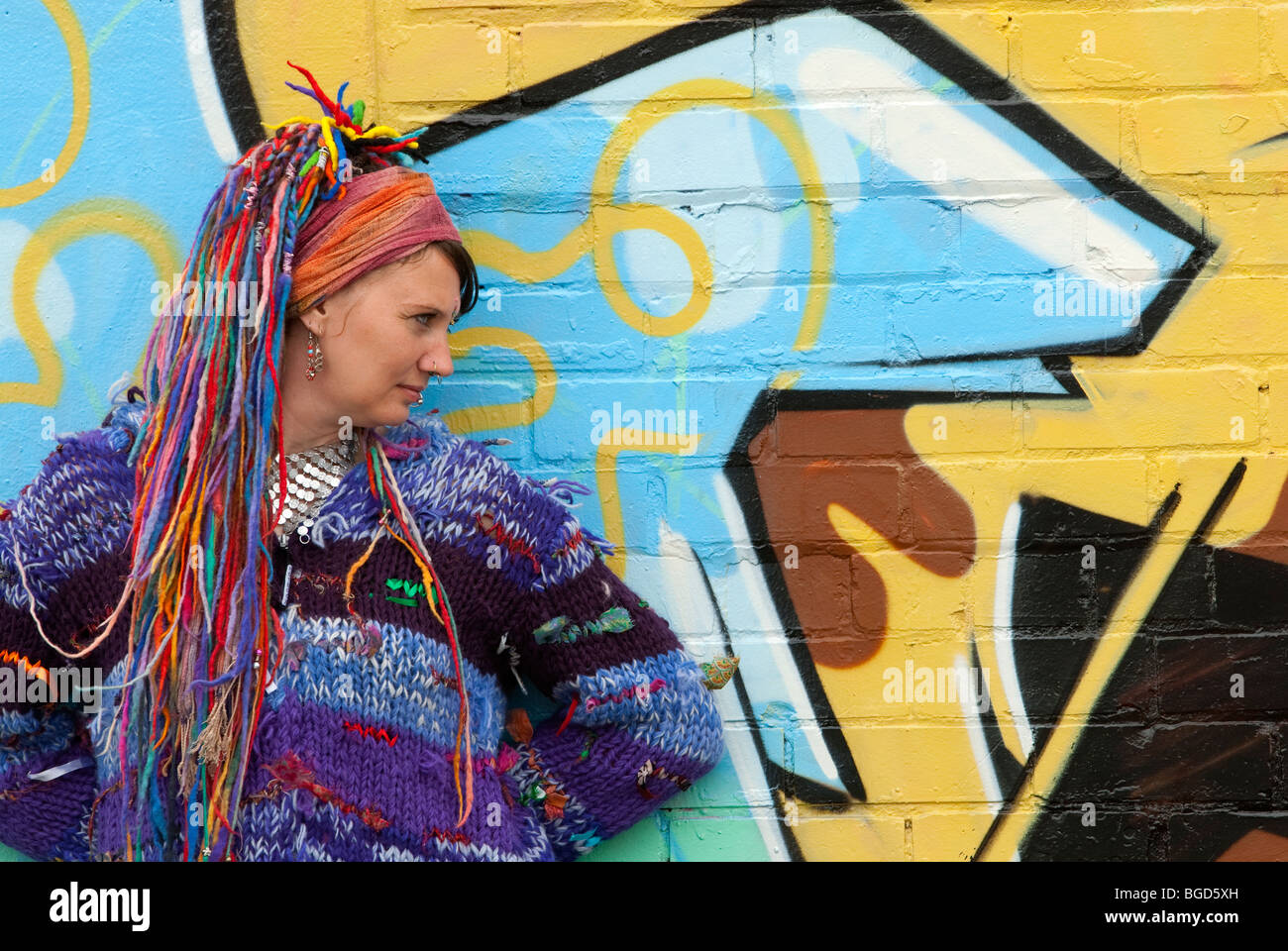 Junge weibliche Hippie mit Multi coloriertes Haar gegen Graffitiwand voll Modell veröffentlicht Stockfoto
