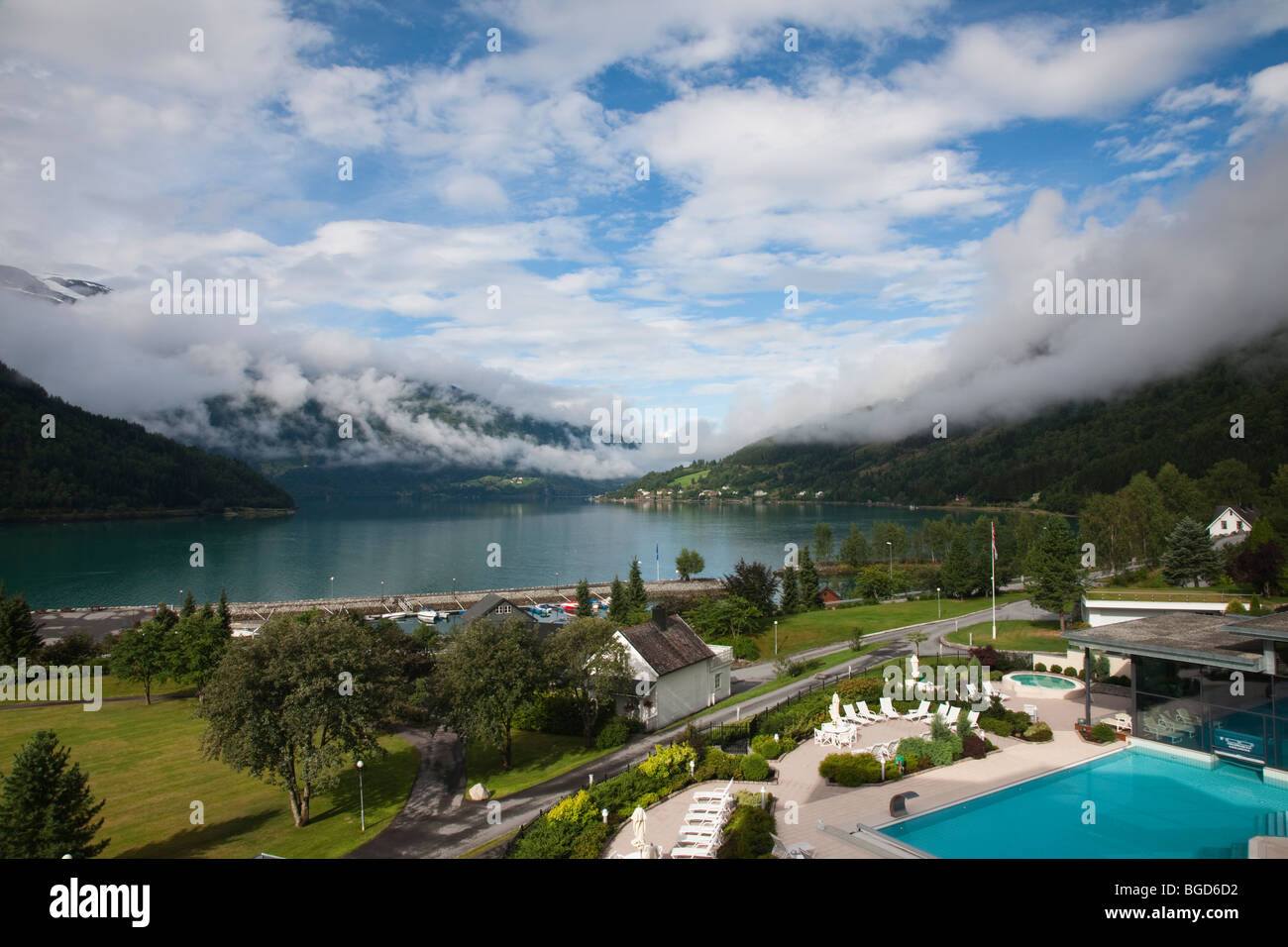 Landschaftlich schöne Der Nordfjord, See Loen von Hotel Alexandra, Loen Norwegen, schneebedeckten Berge niedrige misty Wolken blauer Himmel negativen Raum Stockfoto