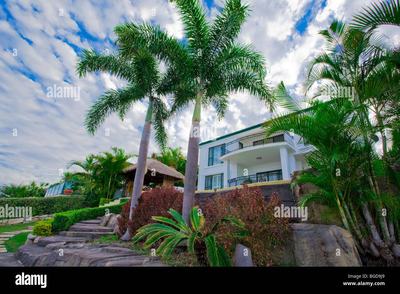 Garten mit Palmen und Bali Hütte vor Waterfront Villa Stockfoto