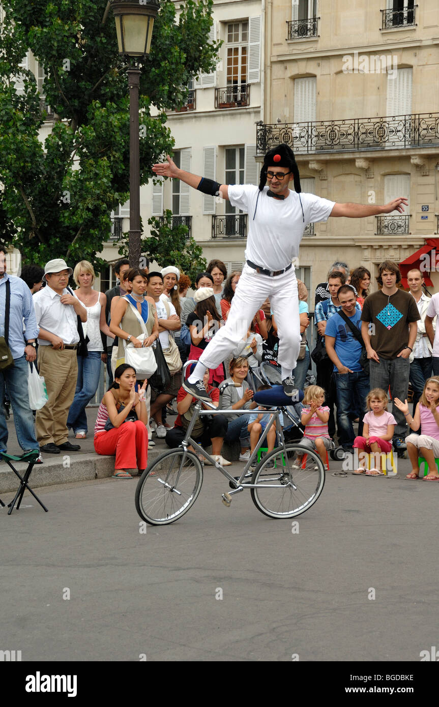 Straßentheater, Street Performer oder Street Entertainer Balancing on Bicycle, Pont Saint Louis, Île Saint Louis, Paris, Frankreich Stockfoto