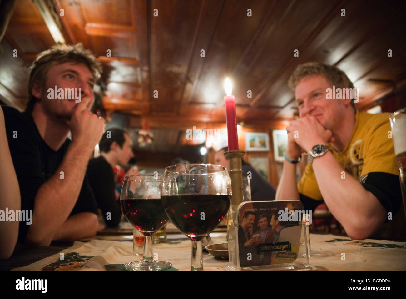 Jugendliche Freunde sat trinken Rotwein um einen Tisch im 'U-Bahn' apres ski Bar in St. Anton, Österreich, Europa. Stockfoto