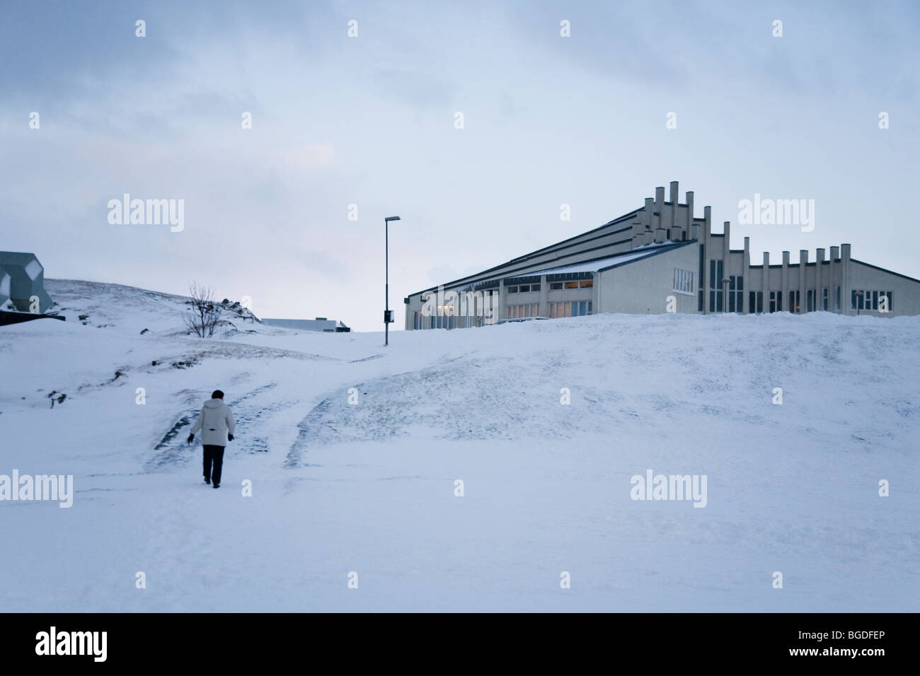 Person zu Fuß in Richtung Vidistadakirkja Kirche im Winter. Hafnarfjordur, größere Fläche, Island. Stockfoto